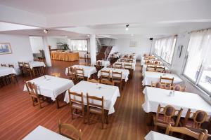 a dining room with white tables and wooden chairs at City Hotel in Caxias do Sul
