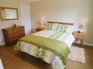 a bedroom with a bed with green and white sheets and a mirror at Coombehayes Lodge in Uplyme