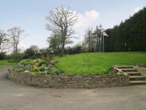 a garden with a stone wall and flowers in a park at Coombehayes Lodge in Uplyme