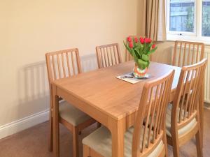 a wooden table with chairs and a vase of flowers on it at Rothbury Cottage in Rothbury