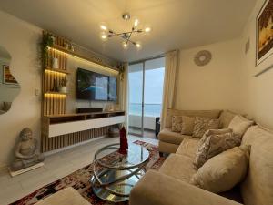a living room with a couch and a tv at Ocean Blue, Vista Frontal Al Mar in Lima