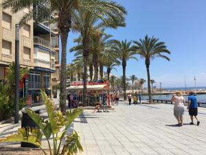 eine Gruppe von Menschen, die auf einem Bürgersteig in der Nähe des Wassers spazieren in der Unterkunft Isla Verde Apartment in Torrevieja