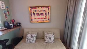a couch with two pillows sitting under a painting at Apartamento Cambui - Centro de Convivência in Campinas