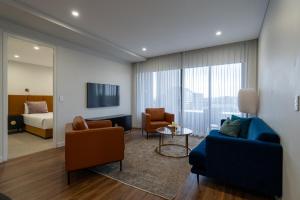 彭里斯Astina Suites, Penrith的客厅里有一张沙发、几把椅子和一张床