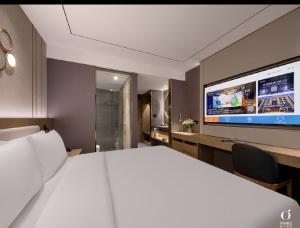 una camera d'albergo con un letto grande e una TV di Orange Hotel Beijing Yizhuang Rongjing West Street a Pechino
