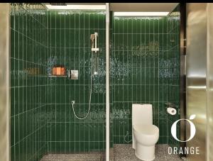 e bagno piastrellato verde con servizi igienici e doccia. di Orange Hotel Beijing Yizhuang Rongjing West Street a Pechino