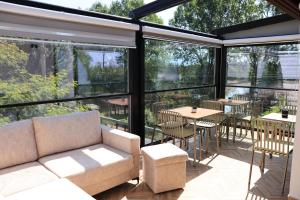 a screened in porch with a couch and tables and chairs at Villa Osmani in Shkodër