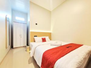 a bedroom with a large bed with a red blanket at RedDoorz Syariah at DNA Home Seturan Yogyakarta in Seturan +25 photos
