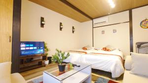 two beds in a room with a tv and a couch at 名鉄名古屋まで7分1棟貸し切り駐車場あり in Nishi-biwashima