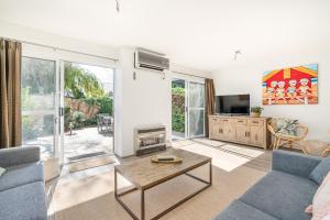 Una sala de estar con un sofá y un televisor. en Abbys Villa - 3BR - Pool - Tennis - Family, en Broadwater