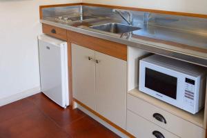 a kitchen with a sink and a microwave at Bay View Terrace Studio 1 in Tataraimaka
