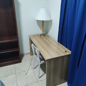 Un escritorio con una lámpara y una silla junto a una cortina azul. en Barú, en La Concepción 1 foto más