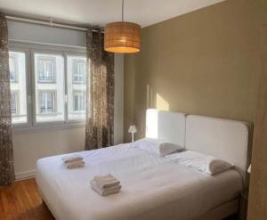une chambre avec un lit blanc avec deux serviettes dessus dans l'établissement SPLENDIDE Appartement pour 4 in front GARE LILLE FLANDRES, à Lille