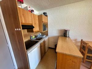a small kitchen with wooden cabinets and a sink at Studio cabine 27m² au pied des pistes de luge, balcon sud, navette gratuite - FR-1-515-236 in Villard-de-Lans