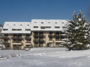 a snow covered apartment building with a tree in the snow at Studio cabine 27m² au pied des pistes de luge, balcon sud, navette gratuite - FR-1-515-236 in Villard-de-Lans +4 photos