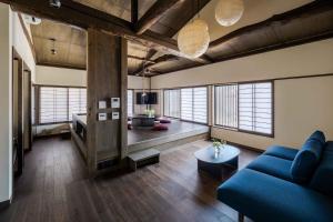 a living room with a blue couch and some windows at Nananohi Machiya House in Takayama