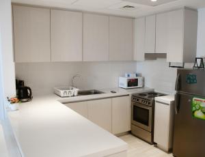une cuisine avec des armoires blanches et un réfrigérateur en acier inoxydable dans l'établissement Bright&spacious 2bd Yas Island, à Abu Dhabi