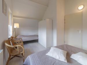 a bedroom with a bed and a chair and a closet at Cozy Zeeland Retreat with a Sauna in Wemeldinge