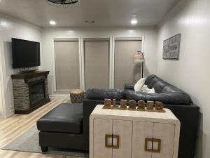 a living room with a black leather couch and a tv at Hugo Cozy Cottage in Hugo
