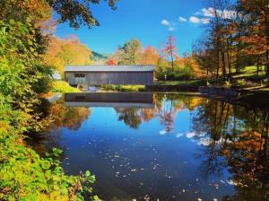 une grange reflétée dans l'eau d'un lac dans l'établissement Green River Cottage, à Guilford