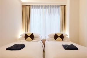 two beds in a hotel room with a window at ASAI Kyoto Shijo in Kyoto
