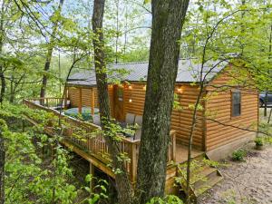 eine Blockhütte im Wald mit einer Terrasse in der Unterkunft CREEKSIDE SNUG wd HOTTUB in Stanton