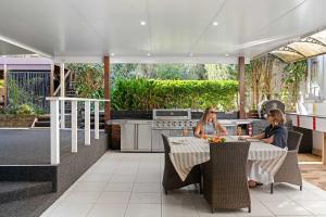 カラウンドラにあるCaloundra Beach Break - 3BD Family Homeの屋外キッチンのテーブルに座っている2人の女性