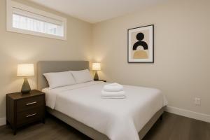una camera con un letto bianco, un comodino e 2 lampade di Spacious 4BD Home in Vancouver a Vancouver Altre 12 foto
