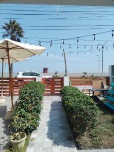 eine Terrasse mit einem Tisch, einem Sonnenschirm und Büschen in der Unterkunft Departamento luminoso frente de la playa Huanchaco in Huanchaco