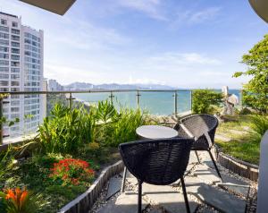 a patio with a table and chairs overlooking the ocean at MissBamboo Hotel Nha Trang in Nha Trang