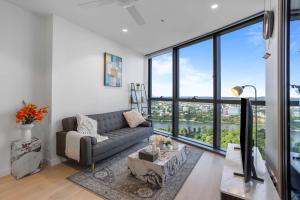 a living room with a couch and large windows at Your QW Escape - Pool Gym & Stunning Sky Deck View in Brisbane