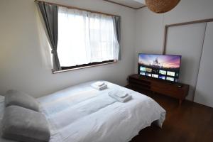 a bedroom with a bed and a flat screen tv at Shinkoiwa 3BR house in Tokyo