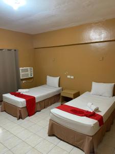 a hotel room with two beds with red sheets at Doña Mercedes in Cebu City
