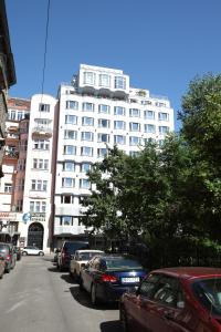 a large white building with cars parked in front of it at Medos Hotel in Budapest