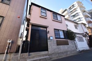 una casa rosa con una puerta negra en una calle en Shinkoiwa 3BR house, en Tokio