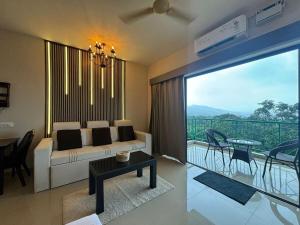 un soggiorno con divano e tavolo e un balcone di Forest Frame - Kudrat Nilaya Valley View with pool a Canacona