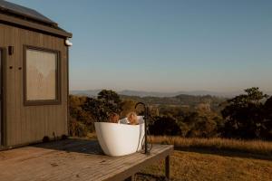 Zwei Kinder sitzen in einer Badewanne auf einer Terrasse in der Unterkunft Tiny Heidi in Imbil