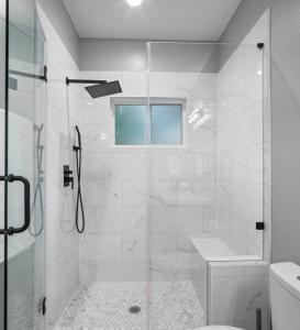 a white bathroom with a shower and a toilet at The Bayou Bungalow- 5 mins to downtown, 10 to NRG, Sleeps 12, Amazing backyard! in Houston +34 photos