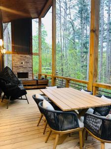 a wooden table and chairs on a porch with a fireplace at Lux Blue Ridge Cabin, Hot tub, Swing, PingPong! in Mineral Bluff +119 photos