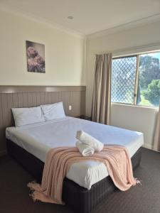 Un dormitorio con una cama grande con una manta encima. en Pittsworth Motor Inn, en Pittsworth