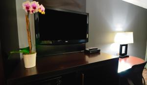a room with a desk with a tv and a flower at Days Inn by Wyndham Downey in Downey