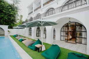 a row of chaise lounges with umbrellas next to a pool at Nuansa Penida Hostel in Nusa Penida