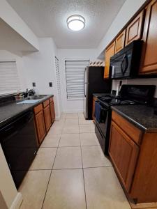 eine Küche mit schwarzen Geräten und einem Fliesenboden in der Unterkunft Charming apartment in Kissimmee, Orlando FL in Kissimmee + 2 Fotos