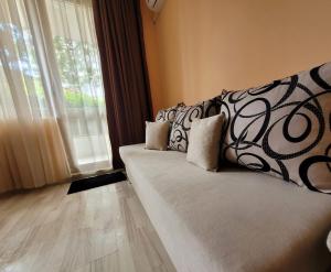 Sofá con almohadas en una habitación con ventana en Sirena Holidays, en Ravda