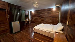 春丕โรงแรมภูน้ำฟ้า - Phunumfha Hotel ชุมแพ的带床和木墙的卧室