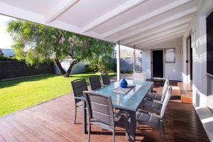 un patio avec une table et des chaises sur une terrasse dans l'établissement Gifford Getaway - Coastal Home in Dunsborough, à Dunsborough