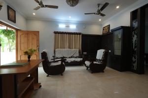 ティルパティにあるPARADISE VILLA A Luxury 5Bhk Home Stayの椅子、テーブル、デスクが備わる客室です。