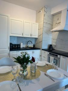 een keuken met een tafel met glazen en bloemen erop bij GoldClass Apartament in Katowice