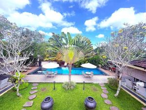 a pool with tables and umbrellas in a yard at Villa Nirvana in Ubud