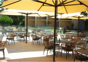 an outdoor patio with tables and chairs and umbrellas at Golden Tulip Avignon Le Paradou in Avignon
